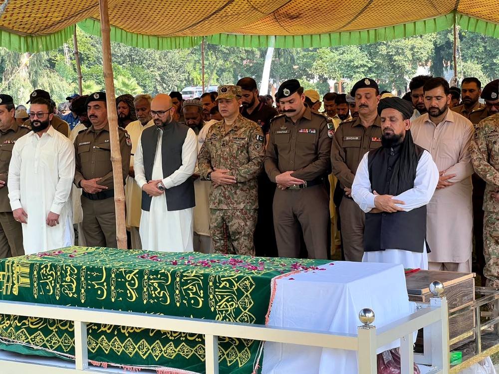 Officers stand at the coffins of the martyred Elite Force personnel during funeral prayers at Police Lines Jhelum