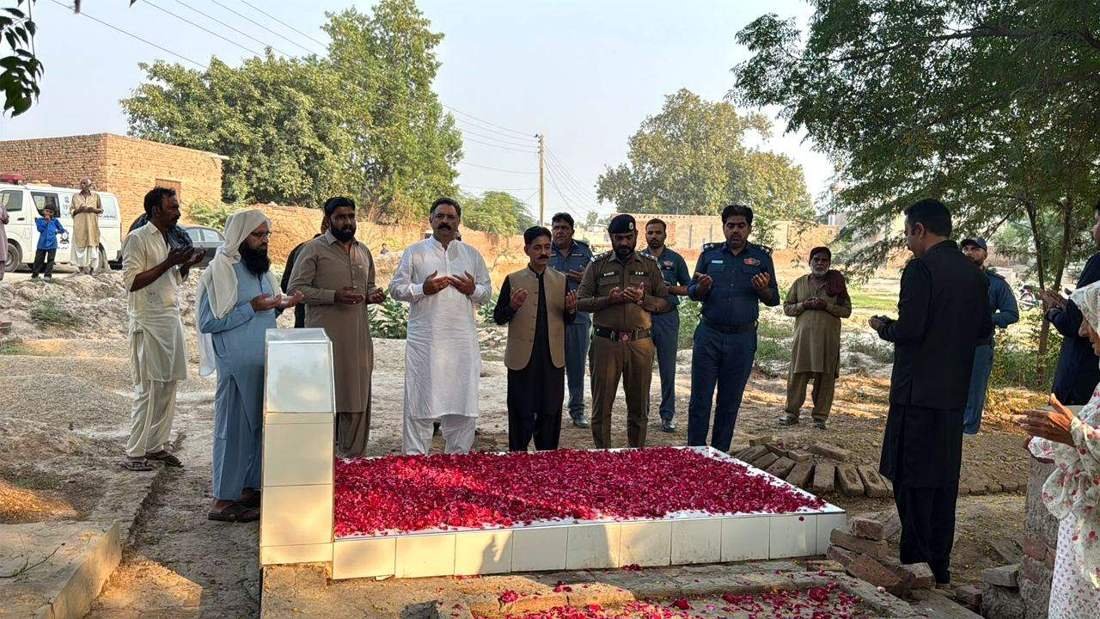 Officers offer Fateha at the grave of Traffic Warden Musawwar Hussain