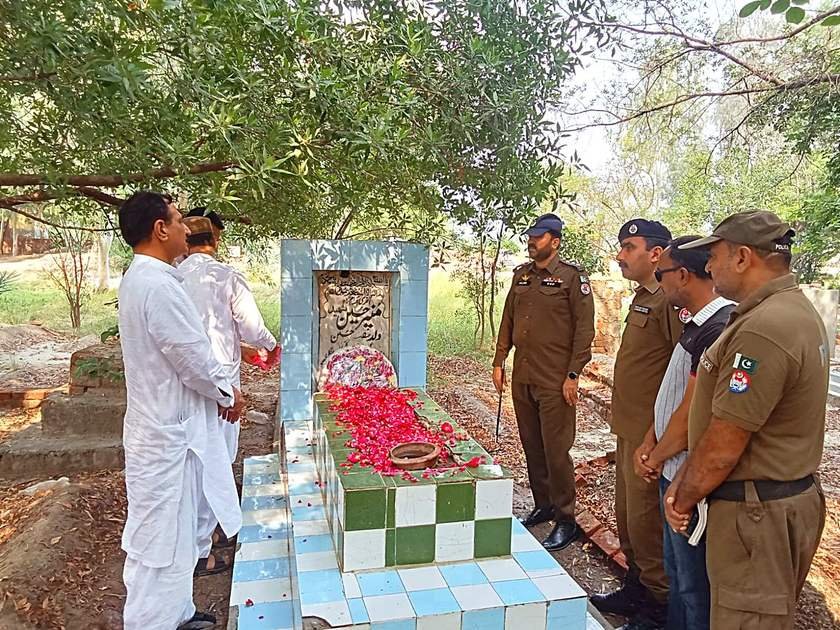 DSP Circle Jaranwala Sajid Mahmood showering rose petals on the grave of martyred Constable Munir Ahmed