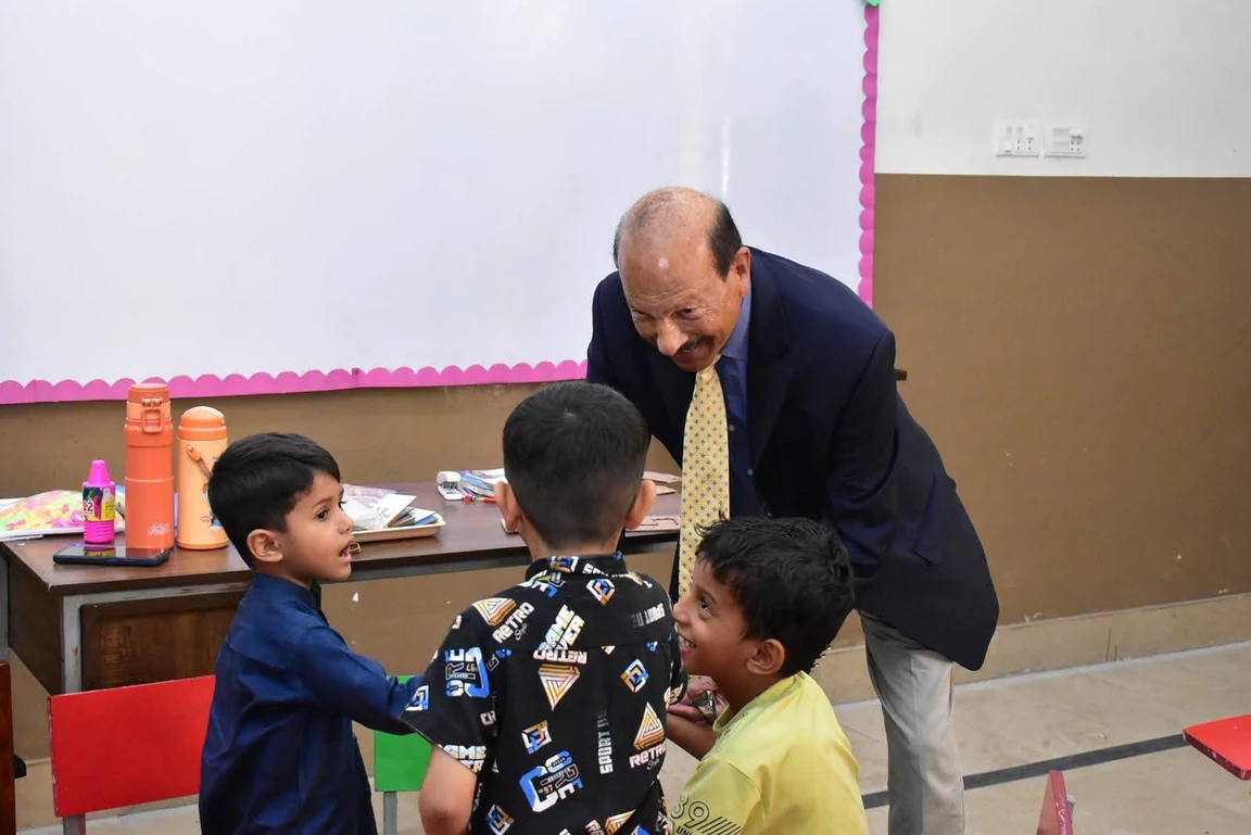 The vice chancellor leans towards smiling small children in a classroom at the University Model School