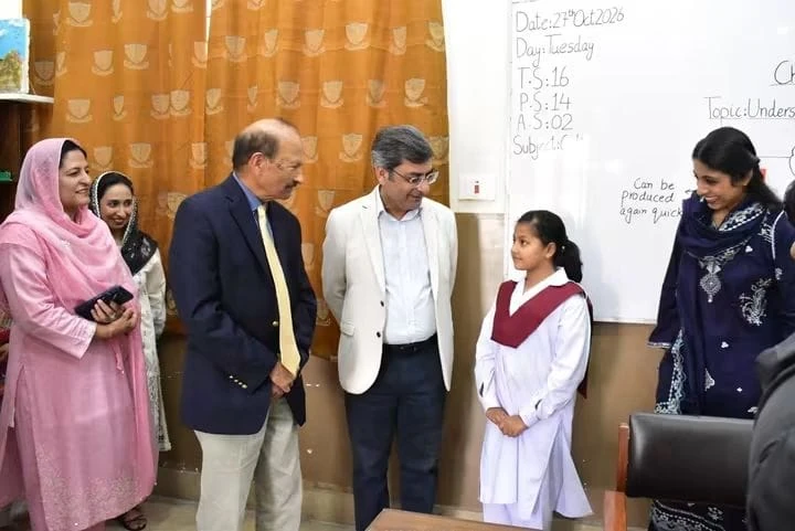 The vice chancellor speaks with a schoolgirl in a classroom