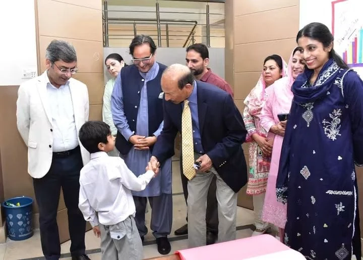 The vice chancellor shakes hands with a small boy as teachers look on