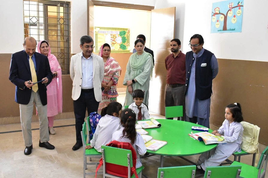 The vice chancellor with officials and children seated around a green table in a classroom