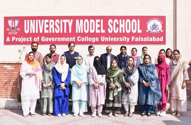 A group photo in front of the University Model School board