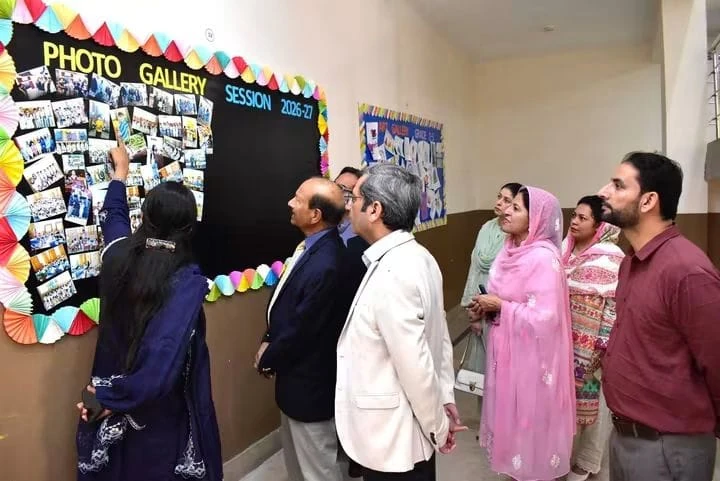 The vice chancellor views a photo gallery wall at the school