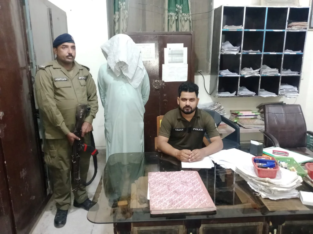 Faisalabad police with an arrested suspect at a police station office.